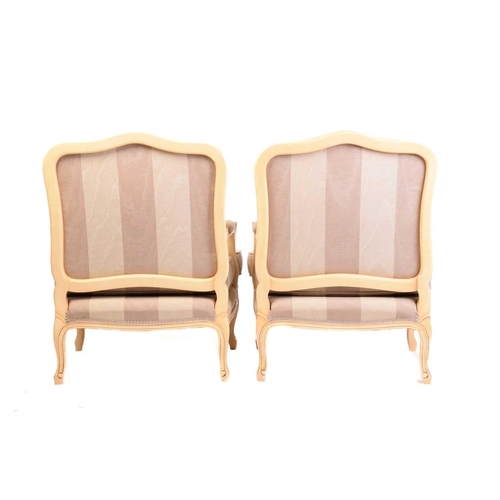 239 - A pair of Louis XV-style ivory painted and parcel gilt fauteuils with arched backs and broad seats a... 