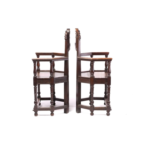 344 - A pair of French carved oak caquetoire armchairs, 19th/20th century, the curved backs carved and pie... 