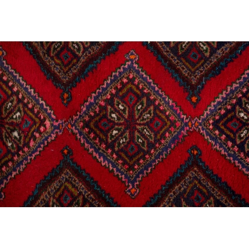 366 - A Hamadan red ground strip runner, with nine lozenges on a central pole within a stylized border. 30... 