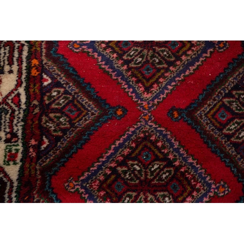 366 - A Hamadan red ground strip runner, with nine lozenges on a central pole within a stylized border. 30... 