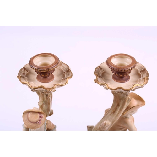 403 - A pair of Royal Worcester figural candlesticks, modelled by James Hadley, as a boy and girl in fine ... 