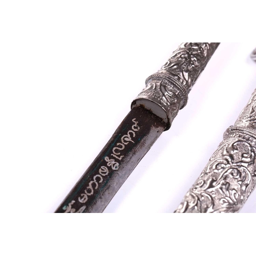 454 - A Thai white metal-mounted short sword with niello worked curving blade the hilt and scabbard of ova... 