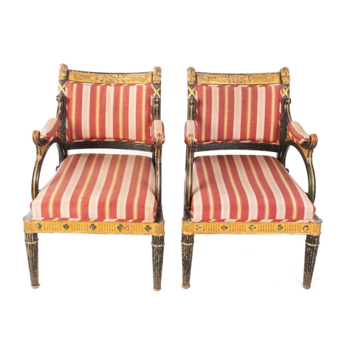 145 - A pair of Regency and later painted and parcel gilt library armchairs with floral carved cresting ra... 