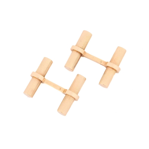 11 - A pair of cufflinks in the style of Cartier; the yellow metal baton links, fluted and held in place ... 