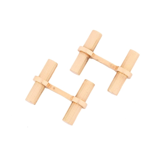 11 - A pair of cufflinks in the style of Cartier; the yellow metal baton links, fluted and held in place ... 