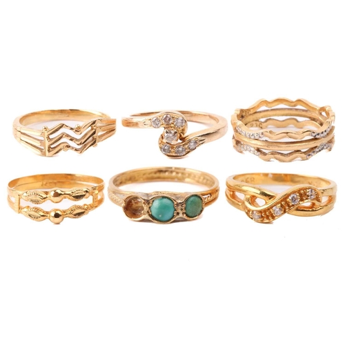131 - Six yellow metal rings; to include a diamond-set crossover ring, size M; a three-stone turquoise hal... 