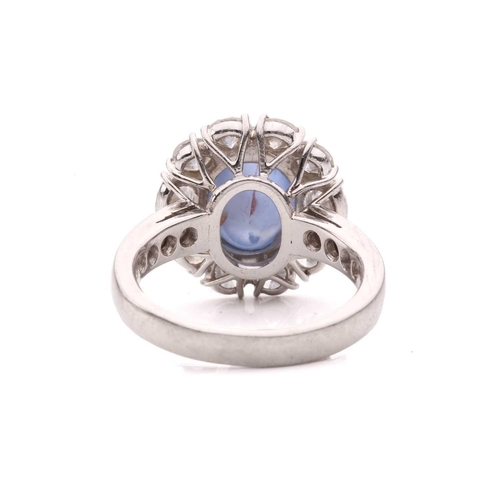 158 - A star sapphire and diamond entourage ring, centred with a star sapphire of 9.7 x 7.7 x 6.0 mm, with... 