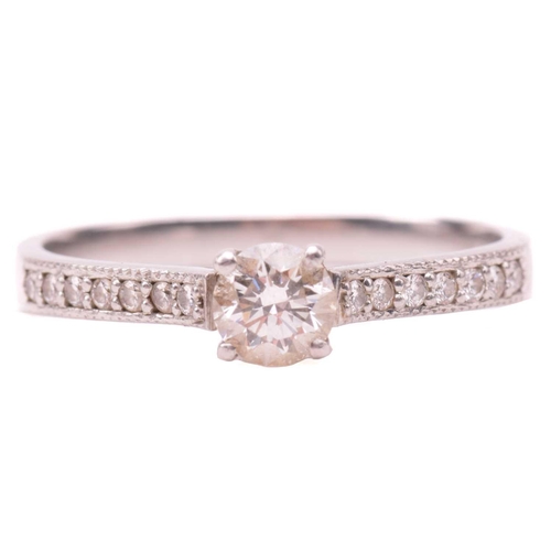 27 - A single stone diamond ring, the round brilliant cut diamond in simple four claw mount, with diamond... 