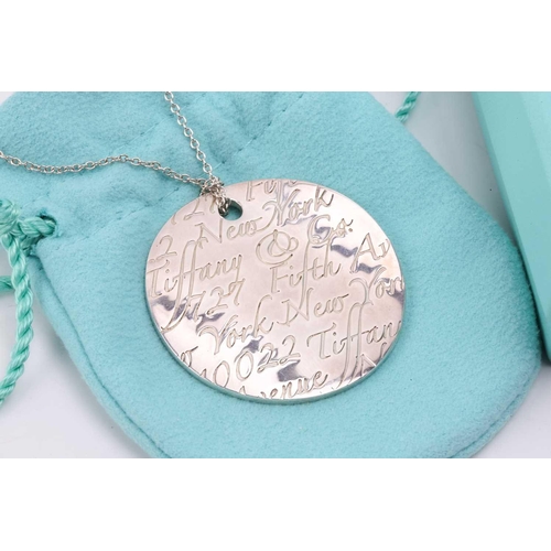 49 - Tiffany & Co. - a silver 'New York Notes' pendant on chain, the curved circular pendant engraved wit... 