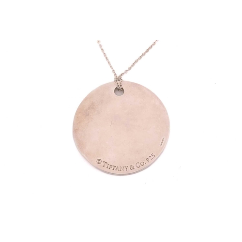 49 - Tiffany & Co. - a silver 'New York Notes' pendant on chain, the curved circular pendant engraved wit... 