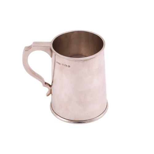 492 - A silver tankard of plain tapering cylindrical form the handle with inverted thumb piece, 11.5cm hig... 