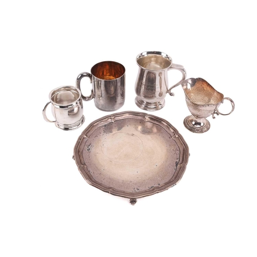 495 - A silver salver on four ball and claw feet together with three 20th-century silver mugs, the small b... 