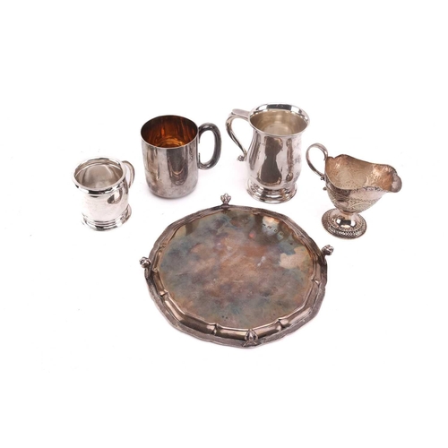 495 - A silver salver on four ball and claw feet together with three 20th-century silver mugs, the small b... 