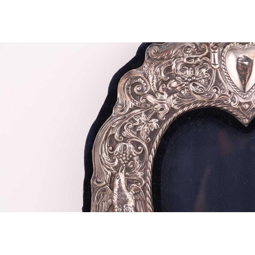 499 - A pair of silver mounted photograph frames with easel stands, the silver mounts surmounted with a he... 