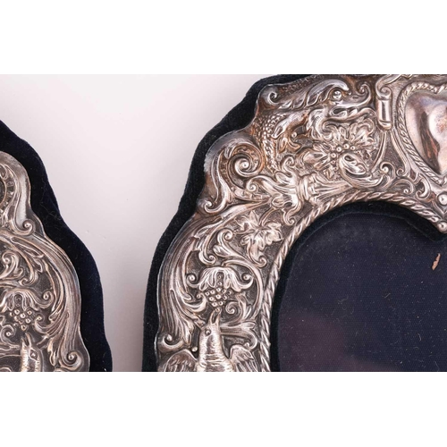 499 - A pair of silver mounted photograph frames with easel stands, the silver mounts surmounted with a he... 