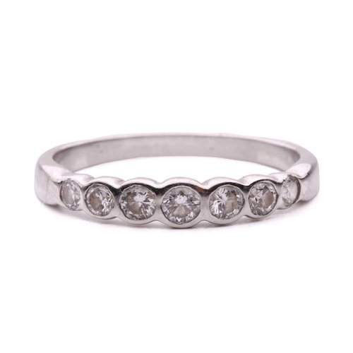 55 - A diamond seven stone half hoop eternity ring, featuring a row of round brilliant cut diamonds with ... 