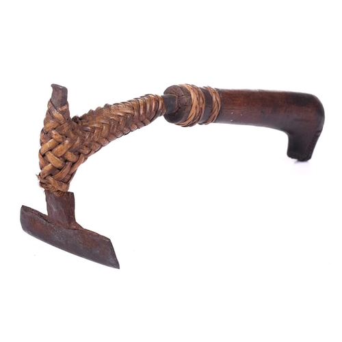 129 - An old tribal adze possibly Oceanic, with a ratan-bound iron blade fitted with naive carved wood dra... 