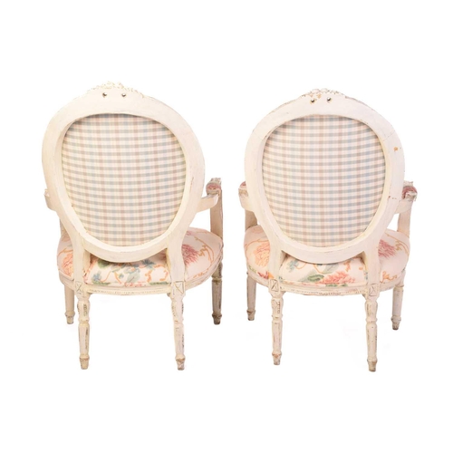 144 - A pair of Louis XVI-style carved painted and distressed fauteuils, 20th century, with cameo-shaped b... 