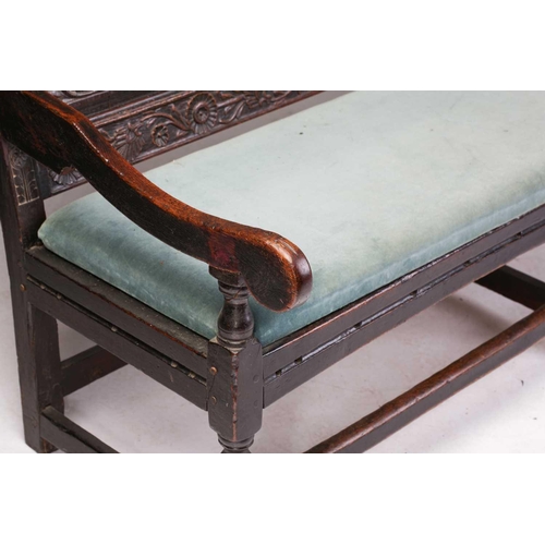 167 - An 18th century, oak settle with carved panel back and shaped arms, the seat rails with pierced rope... 