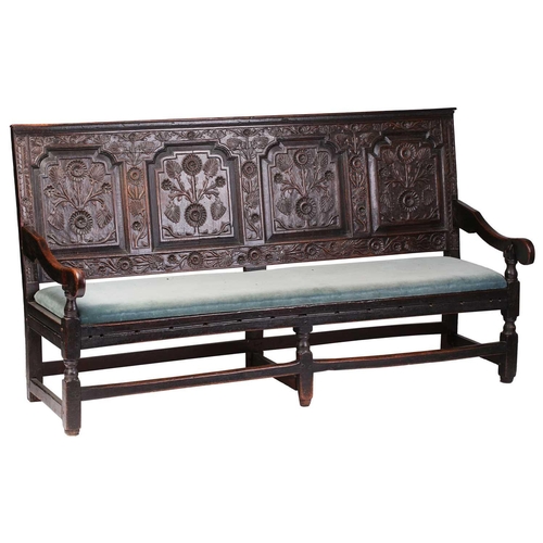 167 - An 18th century, oak settle with carved panel back and shaped arms, the seat rails with pierced rope... 