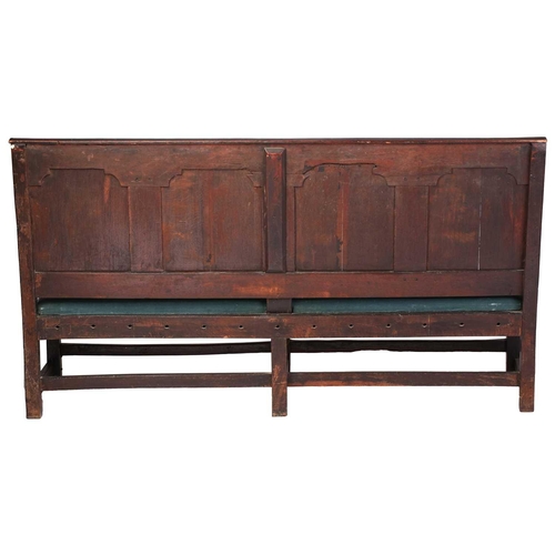 167 - An 18th century, oak settle with carved panel back and shaped arms, the seat rails with pierced rope... 