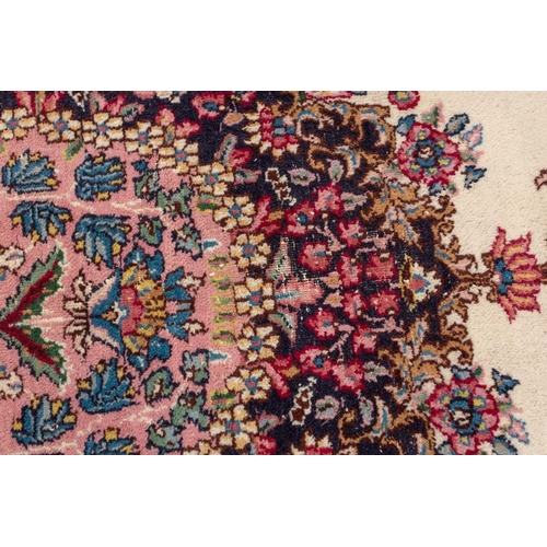 177 - A pair of ivory ground Kerman rugs with central floral medalion and corresponding corners. 128 cm x ... 