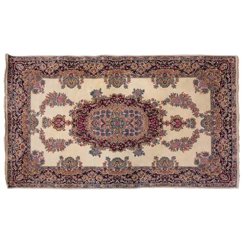 177 - A pair of ivory ground Kerman rugs with central floral medalion and corresponding corners. 128 cm x ... 