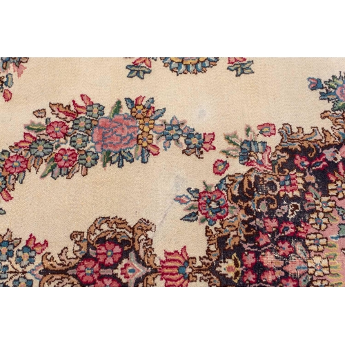 177 - A pair of ivory ground Kerman rugs with central floral medalion and corresponding corners. 128 cm x ... 