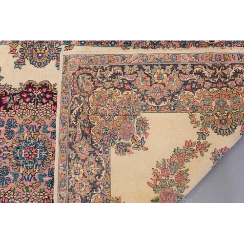 177 - A pair of ivory ground Kerman rugs with central floral medalion and corresponding corners. 128 cm x ... 