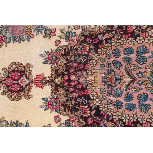 177 - A pair of ivory ground Kerman rugs with central floral medalion and corresponding corners. 128 cm x ... 