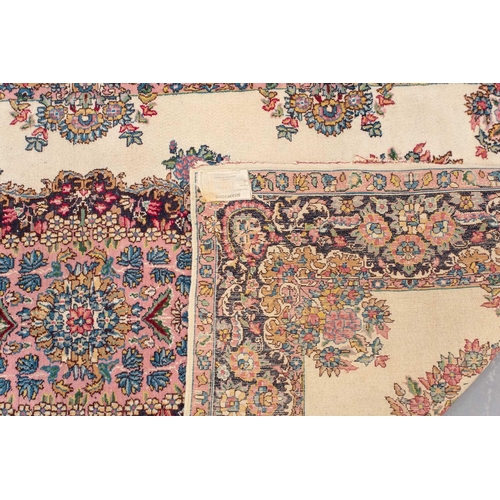 177 - A pair of ivory ground Kerman rugs with central floral medalion and corresponding corners. 128 cm x ... 