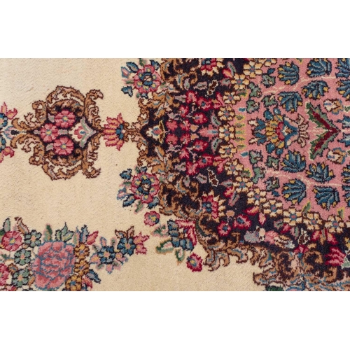 177 - A pair of ivory ground Kerman rugs with central floral medalion and corresponding corners. 128 cm x ... 