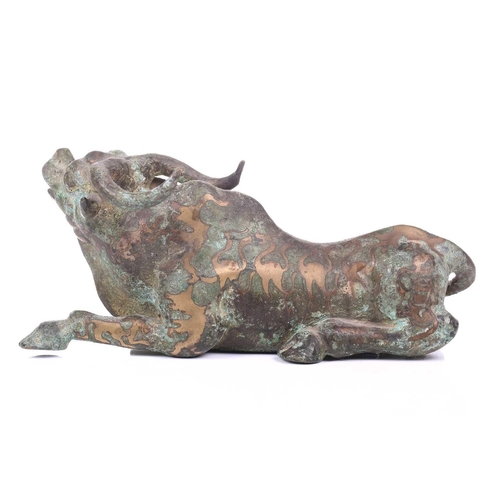 202 - A Chinese bronze and gilt recumbent bull, possibly Zhou dynasty or later, the animal with one leg ou... 