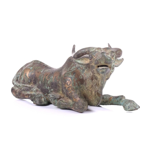 202 - A Chinese bronze and gilt recumbent bull, possibly Zhou dynasty or later, the animal with one leg ou... 