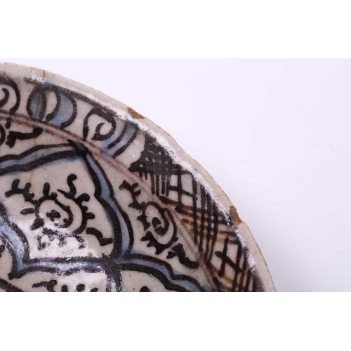 240 - An Islamic faience charger, 17th/18th century, decorated with repeating motifs, within blue and blac... 