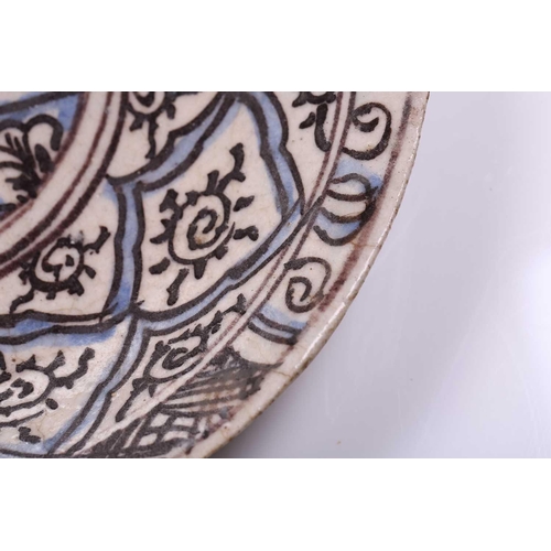 240 - An Islamic faience charger, 17th/18th century, decorated with repeating motifs, within blue and blac... 