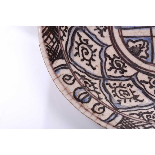 240 - An Islamic faience charger, 17th/18th century, decorated with repeating motifs, within blue and blac... 