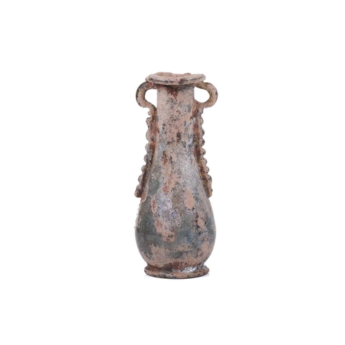 255 - A Roman glass oil flask with a pair of applied ribbon form handles and everted rim over an inverted ... 