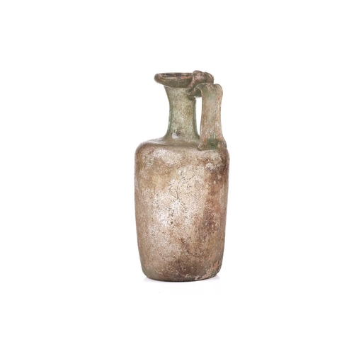 261 - A Roman glass oil ewer of slightly perpendicular form with moulded strap handle to the everted rim, ... 