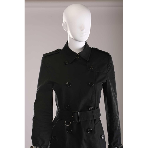 105 - Burberry - a 'Kensington' trench coat in black, lined with Burberry check pattern, double-breasted b... 