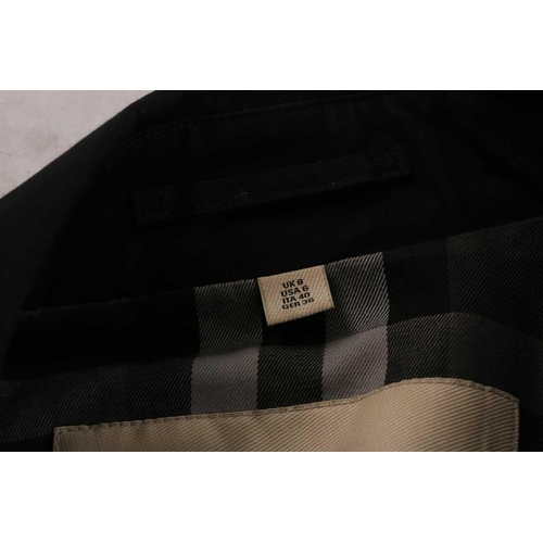 105 - Burberry - a 'Kensington' trench coat in black, lined with Burberry check pattern, double-breasted b... 