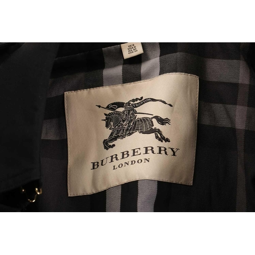 105 - Burberry - a 'Kensington' trench coat in black, lined with Burberry check pattern, double-breasted b... 