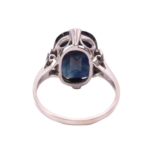 105 - A sapphire solitaire ring features a cushion-cut sapphire of dark blue colour, approximately measure... 