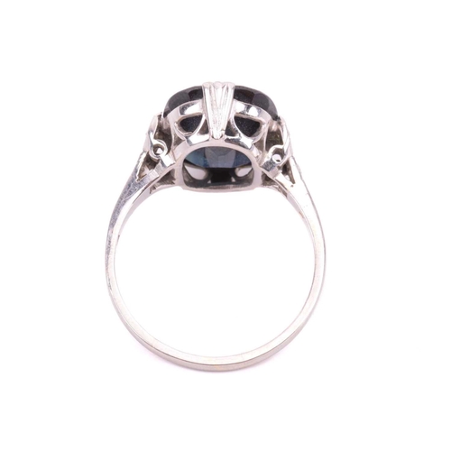 105 - A sapphire solitaire ring features a cushion-cut sapphire of dark blue colour, approximately measure... 