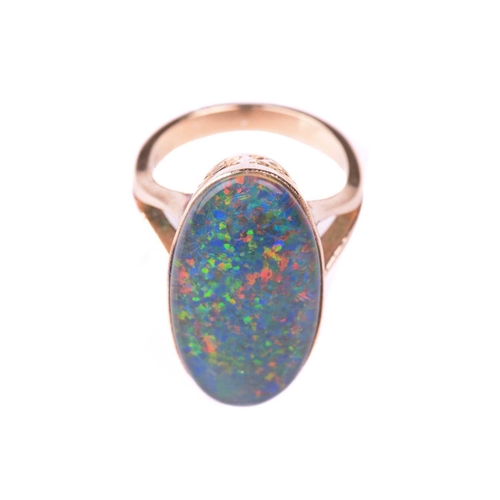 118 - An opal ring, set with an oval opal doublet measuring 24mm x 12mm, to a pierced scrolling gallery wi... 