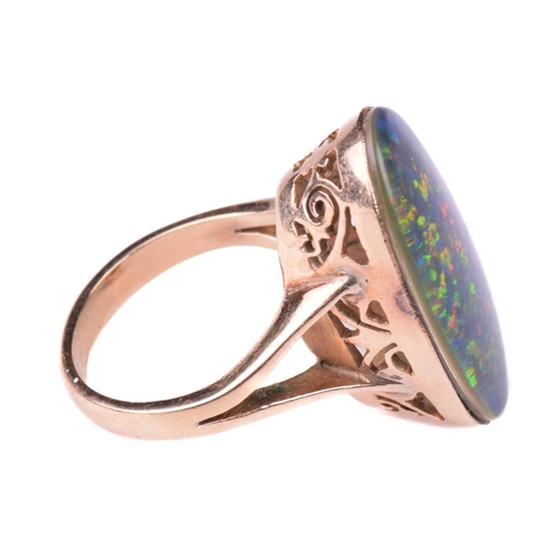 118 - An opal ring, set with an oval opal doublet measuring 24mm x 12mm, to a pierced scrolling gallery wi... 