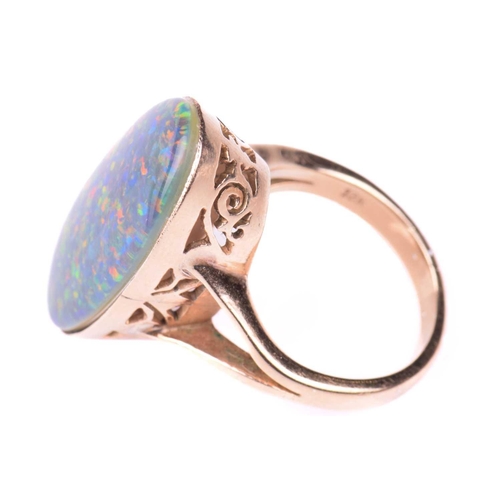 118 - An opal ring, set with an oval opal doublet measuring 24mm x 12mm, to a pierced scrolling gallery wi... 