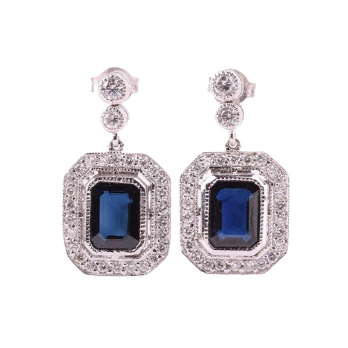 124 - A pair of sapphire and diamond pendant earrings, each with a central emerald cut sapphire measuring ... 