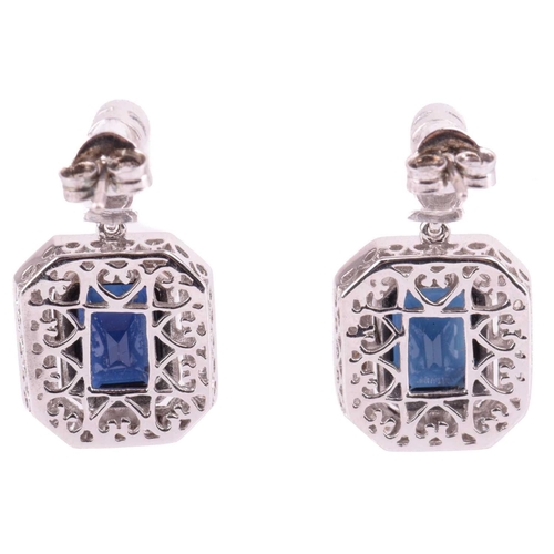 124 - A pair of sapphire and diamond pendant earrings, each with a central emerald cut sapphire measuring ... 