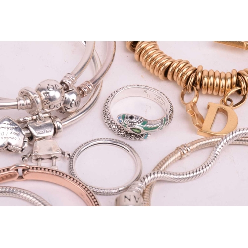 128 - A collection of branded jewellery comprising ten Pandora bangles some with charms, a Thomas Sabo sna... 